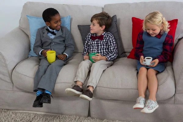 Business kids having drinks on sofa — Stock Photo, Image