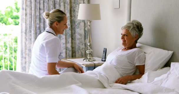 Orvos egymásra hatók-val magas rangú nő ágyon a hálószobában — Stock videók