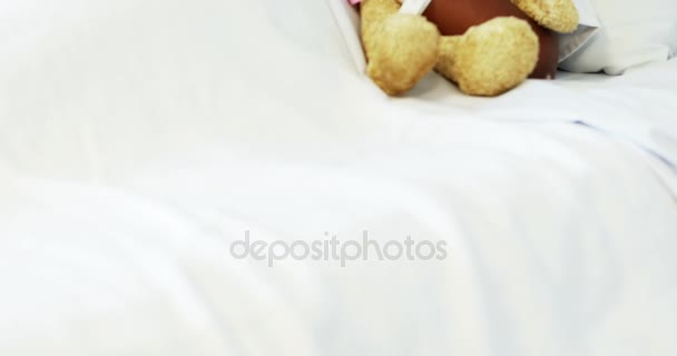 Хвора дівчина відпочиває з плюшевим ведмедем на ліжку — стокове відео