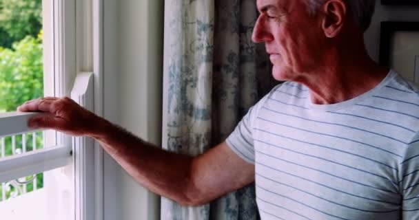 Hombre mayor parado junto a la ventana — Vídeos de Stock