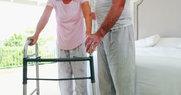 Senior man helping woman to walk with walker — Stock Video