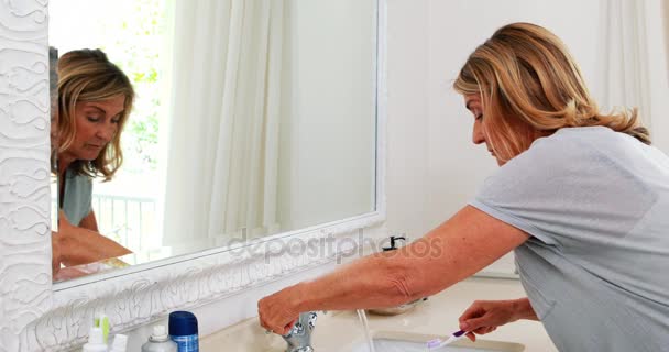 Senior vrouw haar tandenpoetsen in de badkamer — Stockvideo