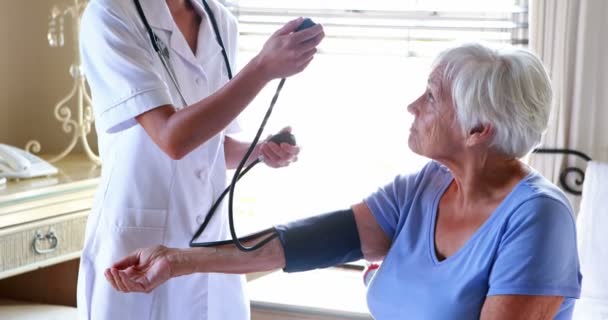 Médico que comprueba la presión arterial de la mujer mayor — Vídeo de stock