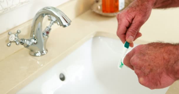 Starší muž dát zubní pastu na kartáček v koupelně — Stock video