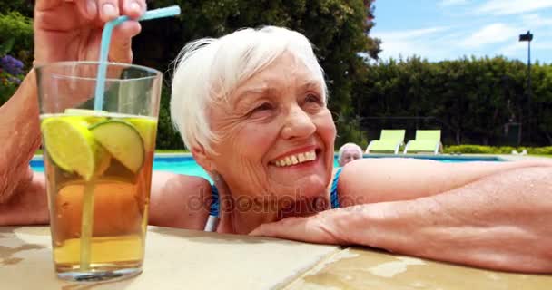 Mujer tomando un vaso de té helado en la piscina — Vídeo de stock