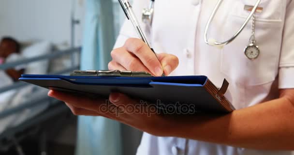 Doctora escribiendo en un portapapeles — Vídeo de stock