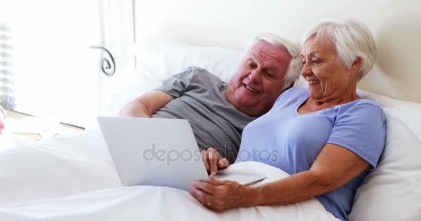 Happy senior couple using laptop on bed — Stock Video