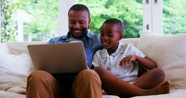 Feliz padre e hijo usando el portátil en la sala de estar — Vídeos de Stock