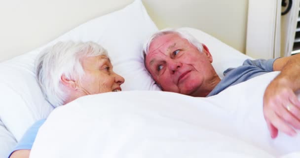 Feliz pareja de ancianos interactuando entre sí mientras están acostados en la cama — Vídeo de stock