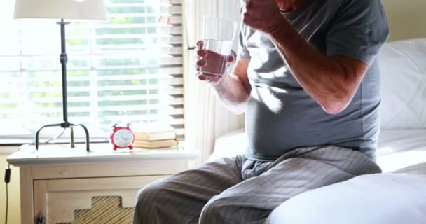Старший мужчина принимает лекарства в спальне — стоковое видео