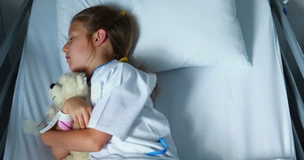 Sick girl resting with teddy bear on bed — Stock Video