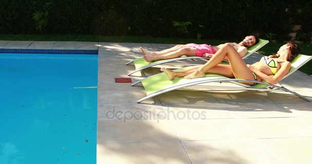 Couple relaxing on lounge chairs at poolside — Stock Video