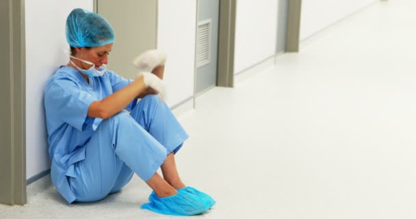 Грустный хирург сидит на полу в коридоре — стоковое видео