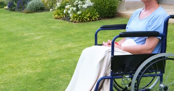 Mujer mayor pensativa sentada en silla de ruedas — Vídeo de stock