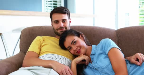 Улыбающаяся пара отдыхает на диване — стоковое видео