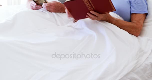 Ευτυχισμένο ζευγάρι ανώτερος ανάγνωση βιβλίων στο κρεβάτι — Αρχείο Βίντεο