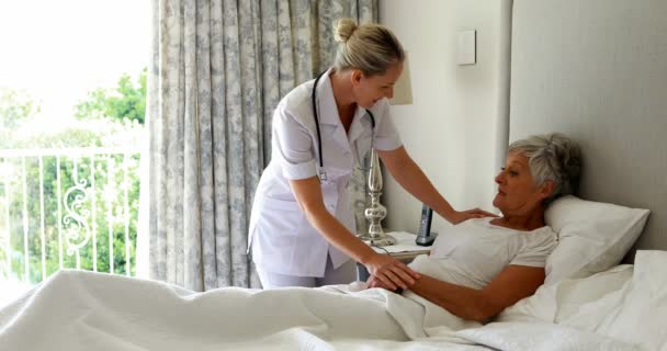 Läkare tröstande senior kvinna på sängen i sovrummet — Stockvideo