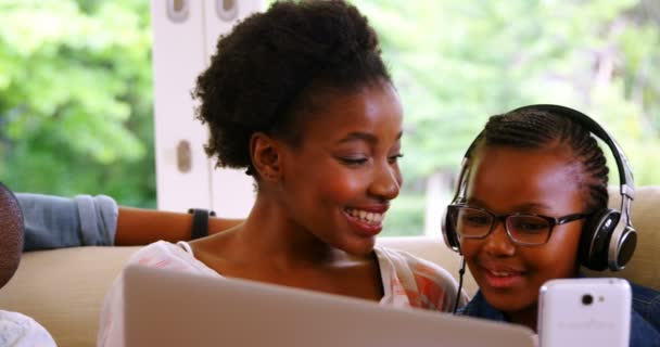 Pais e filhos usando laptop e smartphone no sofá — Vídeo de Stock