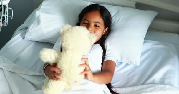 Девушка отдыхает в постели с плюшевым мишкой — стоковое видео