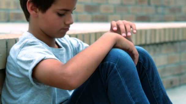 Kampüs içinde tek başına oturan üzgün okul çocuğu — Stok video