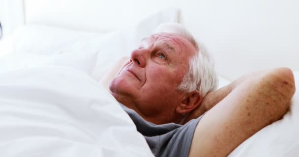 Sonriente hombre mayor acostado en la cama en el dormitorio — Vídeos de Stock