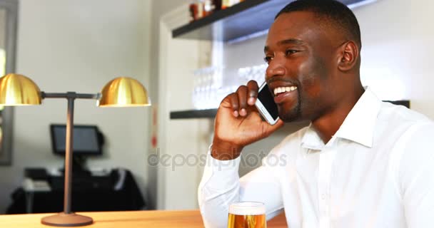 Man praten op mobiele telefoon terwijl het hebben van bier aan balie — Stockvideo