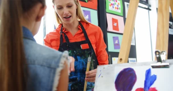 Вчителька допомагає школярці в класі малювання — стокове відео