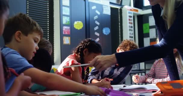 Учитель помогает школьникам с домашним заданием — стоковое видео