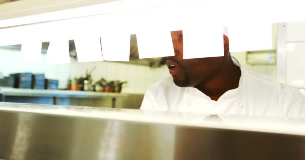 Chef mirando la lista de pedidos mientras sirve comida en la estación de pedidos — Vídeos de Stock