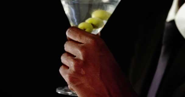 Андрогінний чоловік п'є коктейль на чорному тлі — стокове відео
