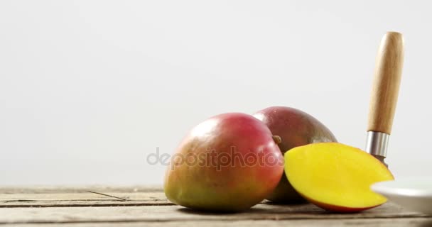 Половинчатый и рубленый манго с ножом на деревянном столе — стоковое видео