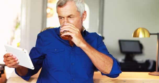 Homme mûr utilisant une tablette numérique tout en ayant de la bière — Video