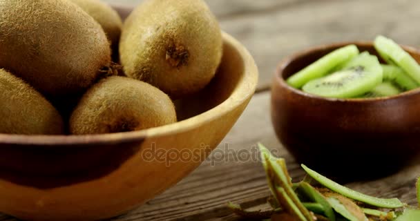 Kiwi rebanado y pelado sobre mesa de madera — Vídeos de Stock