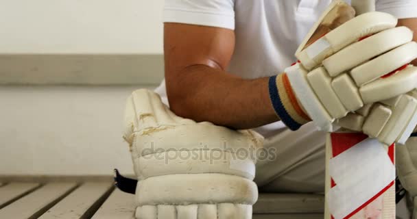 Cricket-Spieler sitzt auf Bank in Umkleidekabine — Stockvideo