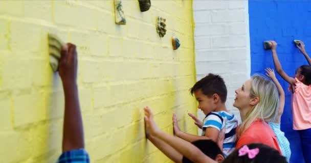 トレーナーのクライミングの壁に子供たちを支援 — ストック動画