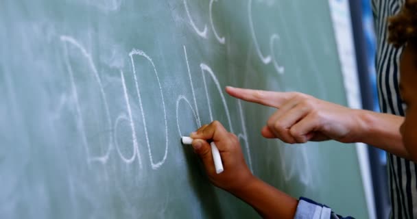 Lehrer unterstützt Schüler beim Schreiben von Alphabet auf Tafel — Stockvideo