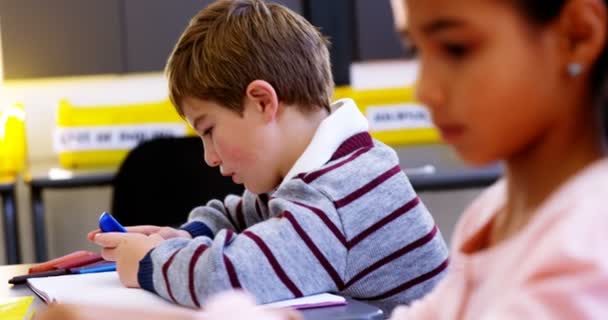 Schoolboy using mobile phone in classroom — Stock Video