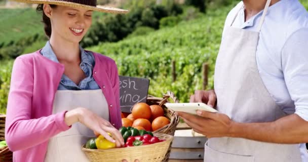 Пара с помощью цифрового планшета, удерживая свежие овощи — стоковое видео