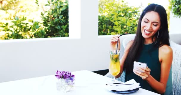 Mujer usando el teléfono móvil mientras bebe mocktail — Vídeos de Stock