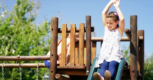 Szczęśliwy uczennica grając na slajdzie w plac zabaw dla dzieci — Wideo stockowe