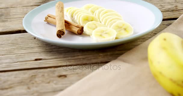 Palitos de canela y plátanos picados en el plato — Vídeo de stock