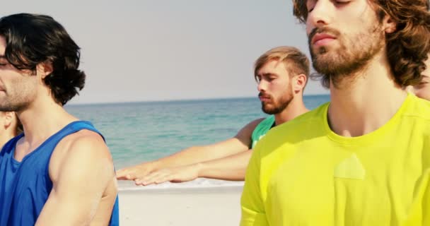 Fit man and woman performing yoga at beach — Stock Video