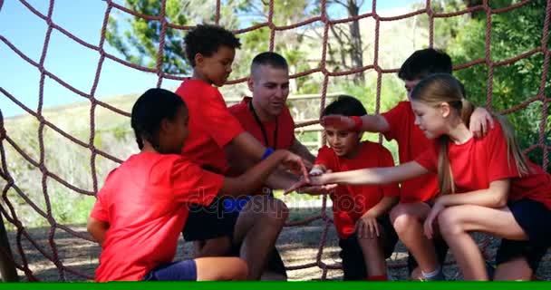 Εκπαιδευτής και τα παιδιά που σχηματίζουν χέρι στοίβα στο στρατόπεδο εκκίνησης — Αρχείο Βίντεο