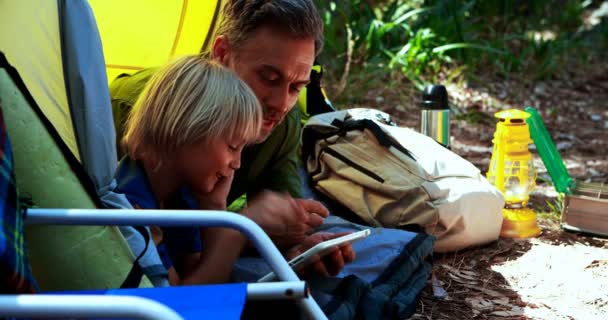 Vader en zoon met behulp van digitale tablet buiten de tent — Stockvideo