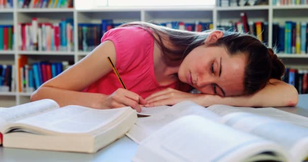 Aluna cansada dormindo na biblioteca enquanto faz lição de casa — Vídeo de Stock