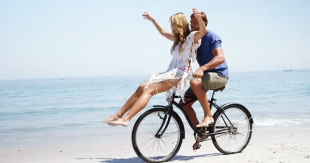 Feliz pareja montando bicicleta en la playa — Vídeo de stock