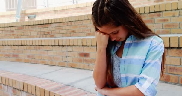 Depressed girl sitting on stairs in campus — Stock Video