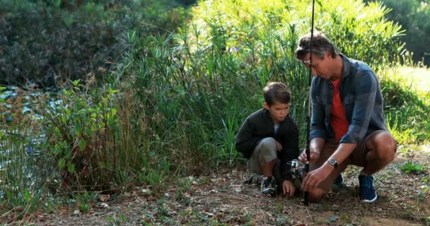 Padre enseñando a su hijo a usar caña de pescar en el parque — Vídeo de stock