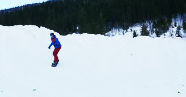 Persoon snowboarden op besneeuwde berg — Stockvideo