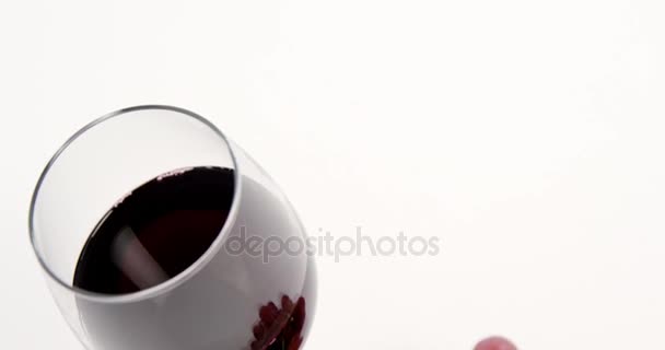 Крупный план красной связки винограда с бокалом красного вина — стоковое видео